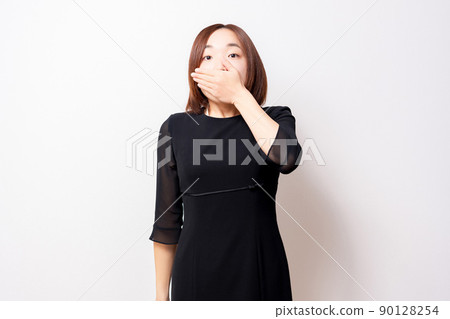 A woman wearing a mourning dress that hides her mouth with her hands A woman wearing a mourning dress that hides her mouth with her hands 90128254