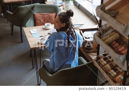 Top view on young cheerful sporty woman with braids smiling while sitting in coffee shop. 90129419