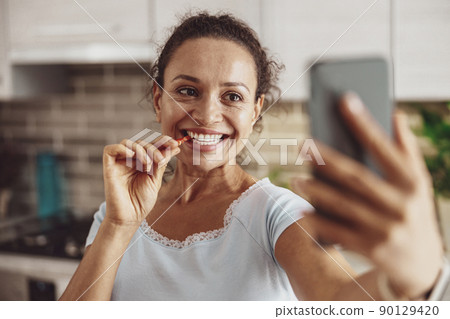 Smiling woman takes a selfie in a piece of sweet pepper in her teeth 90129420
