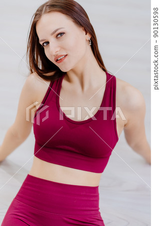 beautiful girl in burgundy tracksuit in fitness room. cosmetics for athletes. 90130598