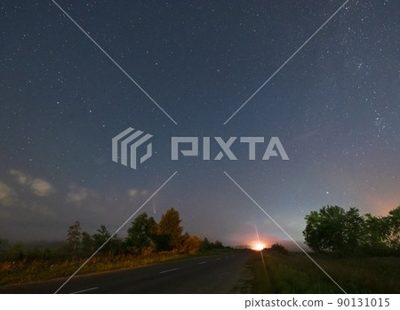 Comet Neowise C2020 F3 as it flies overhead in the summer sky over over meadow near countryside road, Lviv Region, Ukraine. 90131015