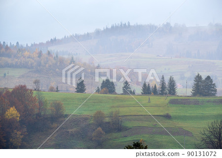 Cloudy and foggy autumn mountains scene. Peaceful picturesque traveling, seasonal, nature and countryside beauty concept scene. Carpathian Mountains, Ukraine. 90131072