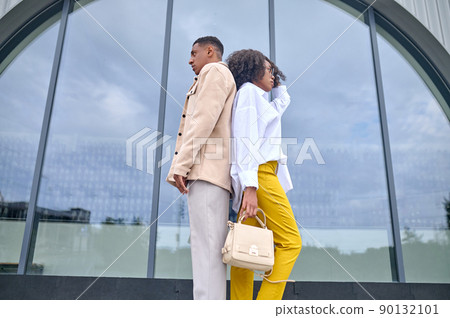 Girl and boy standing with backs to each other 90132101