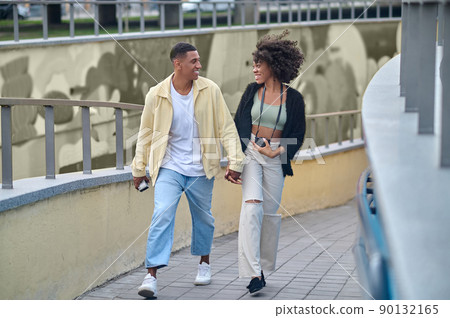 Happy guy and girl walking hand in hand Happy guy and girl walking hand in hand 90132165