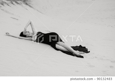 girl in a black long dress in a sandy desert girl in a black long dress in a sandy desert 90132483
