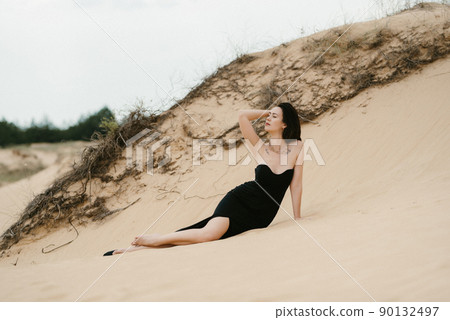 girl in a black long dress in a sandy desert 90132497