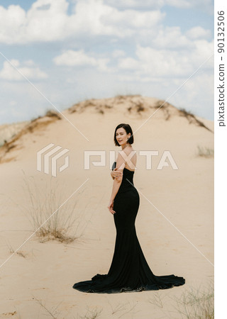 girl in a black long dress in a sandy desert girl in a black long dress in a sandy desert 90132506