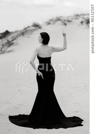 girl in a black long dress in a sandy desert girl in a black long dress in a sandy desert 90132507