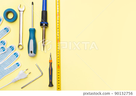 Repair tools on a yellow background. Measuring tape, screwdriver, construction gloves. Place for text. Copy space. Flat lay. Top view. Handyman tool kit. DIY. Advertising for the store. Repair tools on a yellow background. Measuring tape, screwdriver, construction gloves. Place for text. Copy space. Flat lay. Top view. Handyman tool kit. DIY. Advertising for the store. 90132756
