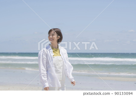 Young woman taking a walk on the beach Young woman taking a walk on the beach 90133094