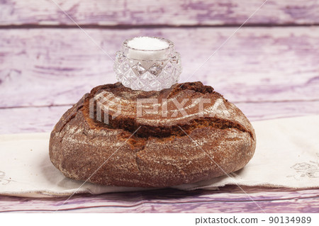 Bread with salt is a traditional symbol of hospitality. Round rye bread with salt shaker on top. 90134989