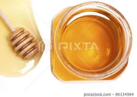 Honey dripping from honey dipper in glass jar, top view. Healthy food concept Honey dripping from honey dipper in glass jar, top view. Healthy food concept 90134994
