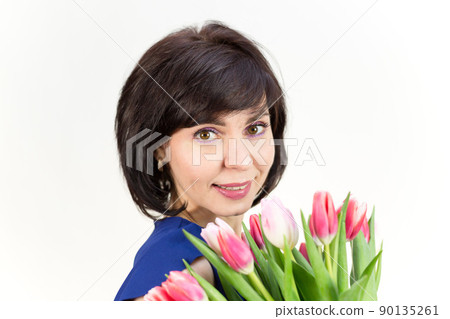 Portrait of an adult woman smiling brunette 40-45 years old with a bouquet of tulips on a white background 90135261