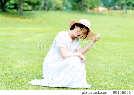 Woman in a straw hat relaxing on the lawn 90136006