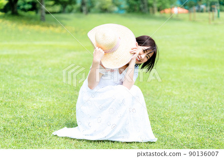 Woman in a straw hat relaxing on the lawn Woman in a straw hat relaxing on the lawn 90136007