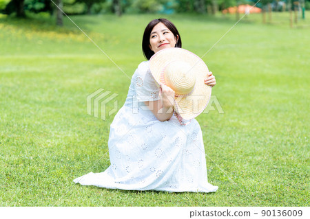 戴著草帽的女人在草坪上放鬆 戴著草帽的女人在草坪上放鬆 90136009