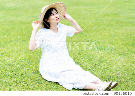 戴著草帽的女人在草坪上放鬆 戴著草帽的女人在草坪上放鬆 90136010