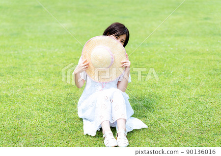 戴著草帽的女人在草坪上放鬆 戴著草帽的女人在草坪上放鬆 90136016