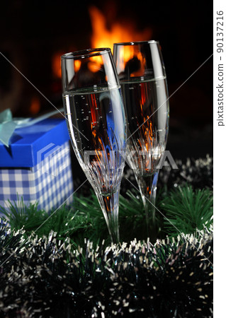 glasses with champagne with christmas entourage, fire as the background glasses with champagne with christmas entourage, fire as the background 90137216