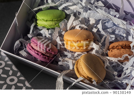 Set of multiple colorful macarons in a gift box, gray and white background 90138149