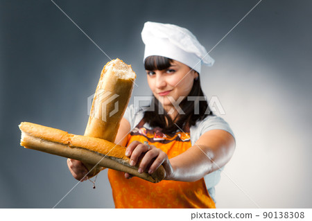 woman cook crossing a french bread, focus on the bread 90138308