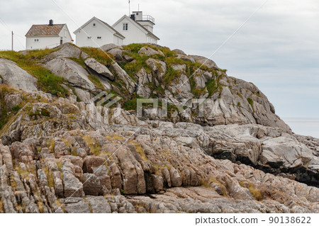 Several white houses stand on the rocky coast of Norway, rocky coast with dramatic sky, the sun breaks through the clouds, sheer cliff Several white houses stand on the rocky coast of Norway, rocky coast with dramatic sky, the sun breaks through the clouds, sheer cliff 90138622