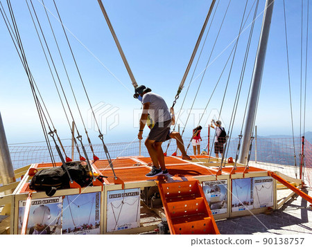 catapult on top of the mountain. entertainment for tourists, active recreation. jump up on a huge elastic band, an adult is dressed in equipment 90138757