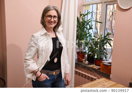 Confident portrait of a smiling stylish elderly European woman, fashion designer, tailor, dressmaker in her own fashion tailor atelier 90139917