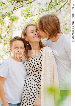 a happy and beautiful mother of two teenage sons in a blooming spring garden.  90139937