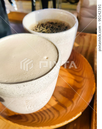 Cappuccino with fragrant milk foam and black Americano on a wooden tray. View from above. Coffee for two. Delicious freshly brewed coffee for breakfast in the cafe 90142391