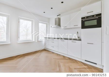 Interior of empty white kitchen with windows and wooden parquet floor Interior of empty white kitchen with windows and wooden parquet floor 90143253
