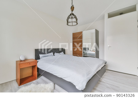 Interior of a bedroom with a small bed in white with laminate flooring in a modern house 90143326
