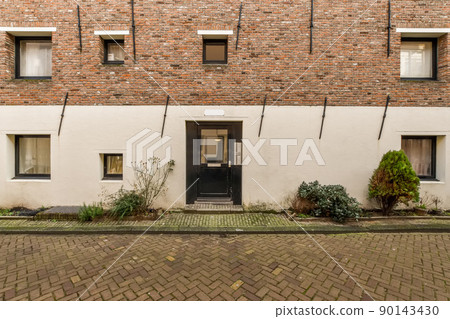 Multi-storey residential building with windows of various formats and a tiled path in front of the house Multi-storey residential building with windows of various formats and a tiled path in front of the house 90143430