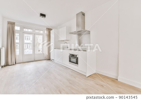 Spacious empty bright room with a corner kitchen in white in a modern house 90143545
