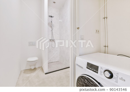 The interior of a modern bathroom with shower, toilet and washing machine in a cozy house 90143546
