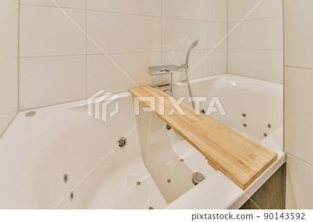 Modern home interior design of light bathroom with white ceramic tiles and big expenisve bathtub and wooden desk 90143592