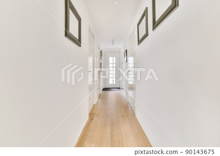 Light narrow hallway with many doors in white walls and glowing lamp over lumber floor 90143675