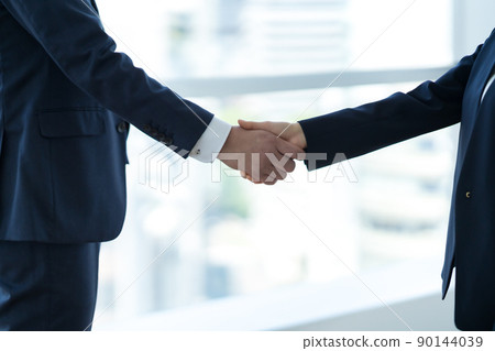 A businessman shaking hands in a sophisticated office A businessman shaking hands in a sophisticated office 90144039