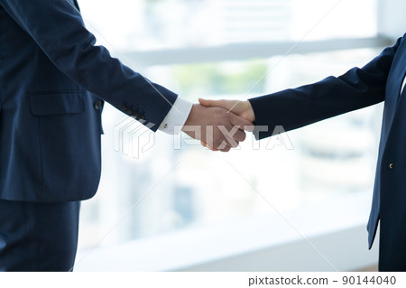 A businessman shaking hands in a sophisticated office 90144040