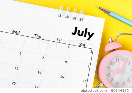 July 2022 desk calendar and pen with plant pot on yellow background. 90144125