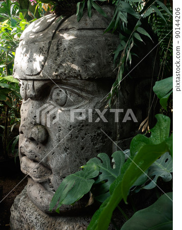 Olmec sculpture carved from stone. Mayan symbol - Big stone head statue in a jungle 90144206