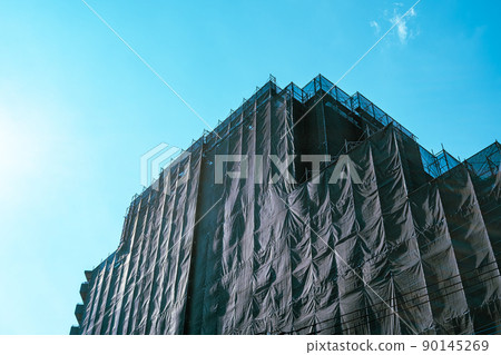 Large-scale condominium repair work A curing net covering the scaffolding and a clear sky light color Large-scale condominium repair work A curing net covering the scaffolding and a clear sky light color 90145269