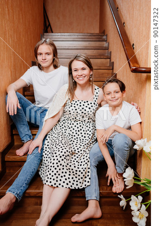 happy and beautiful mother of two teenage sons on the wooden stairs in the house happy and beautiful mother of two teenage sons on the wooden stairs in the house 90147322