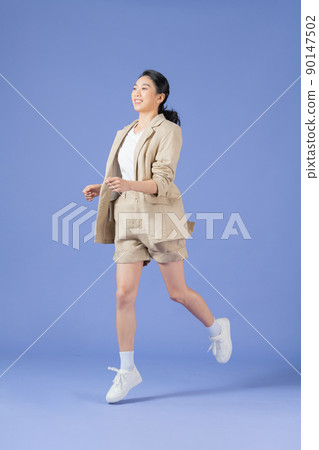 Full length body size photo of girlish cheerful woman jumping stepping smiling isolated purple background 90147502