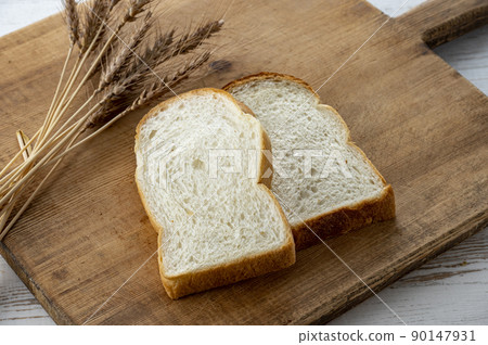 Bread and wheat ears on a cutting board Bread and wheat ears on a cutting board 90147931