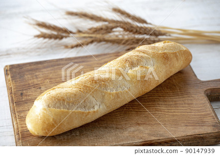 Bread and wheat ears on a cutting board 90147939
