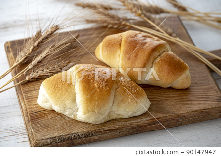 Bread and wheat ears on a cutting board Bread and wheat ears on a cutting board 90147947