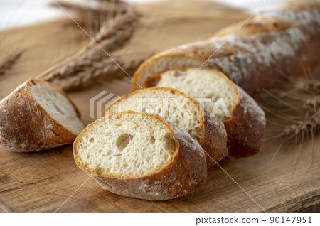 Bread and wheat ears on a cutting board Bread and wheat ears on a cutting board 90147951