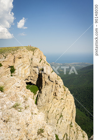 Landscape with mountains, hills and cliffs. A couple stands on a cliff and enjoys it. Vertical photo. Landscape with mountains, hills and cliffs. A couple stands on a cliff and enjoys it. Vertical photo. 90148030