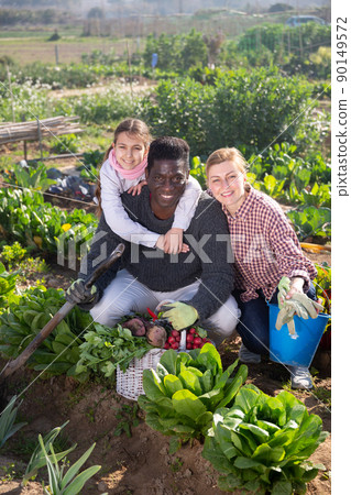 couple of gardeners with daughter holding harvest of fresh vegetables couple of gardeners with daughter holding harvest of fresh vegetables 90149572